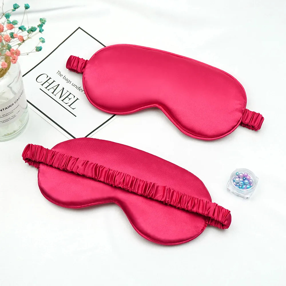 A pink double-sided silk eye mask is shown on a white background next to a box labeled Chanel.