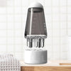A clear glass portable scalp applicator comb with roller balls rests on a white base.