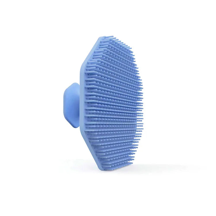 A light blue silicone facial cleaning brush with dense bristles shown against a white background.