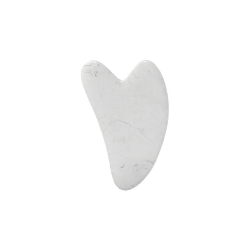 A white heart-shaped jade gua sha facial stone.