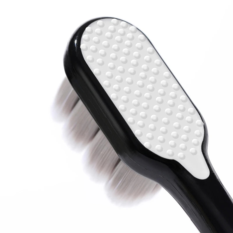 A black toothbrush with a white head and soft bristles is shown against a white background.