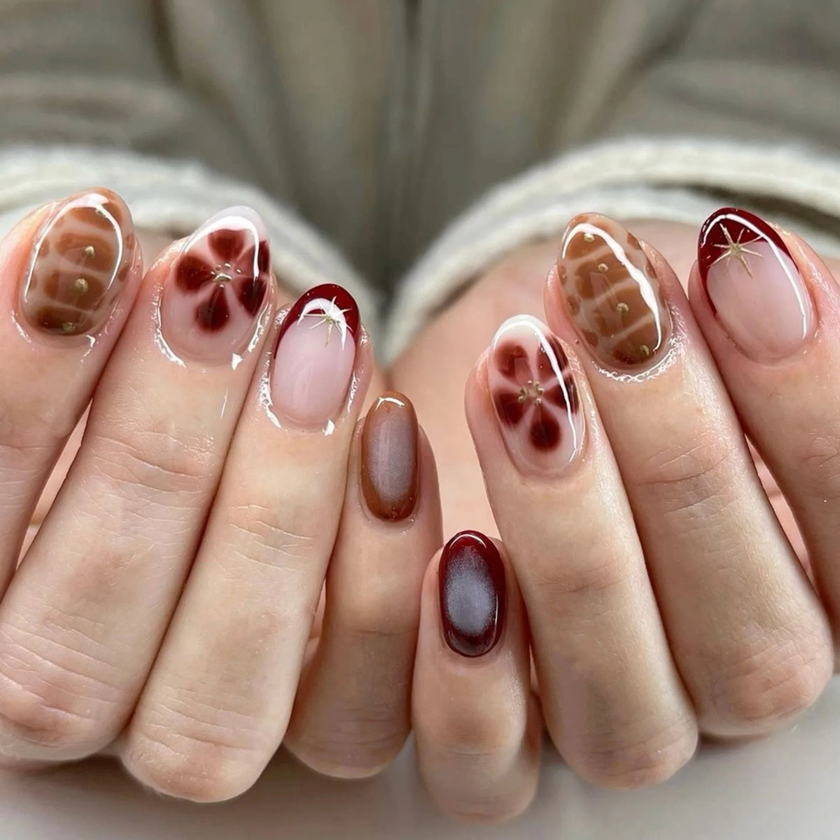 Gros plan d'une main montrant un ensemble de faux ongles à presser français roses avec un dégradé brun-rougeâtre.