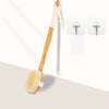 A wooden body exfoliating brush with a long handle and bristles, shown next to two white shower heads.
