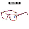 A pair of pink and purple patterned magnifying reading glasses.