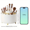 White rotating makeup organizer holding various brushes and tools next to an iPhone 14 Pro.