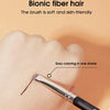 A hand is shown applying color to a finger using a precision makeup brush for hair coloring.