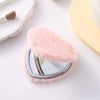 A heart-shaped foldable travel makeup mirror covered in soft pink faux fur resting on a white surface.