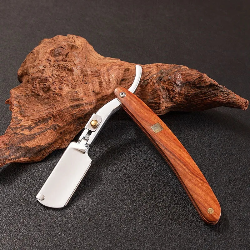 A professional wood handle shaving razor with a wooden handle and silver blade rests on a piece of bark.