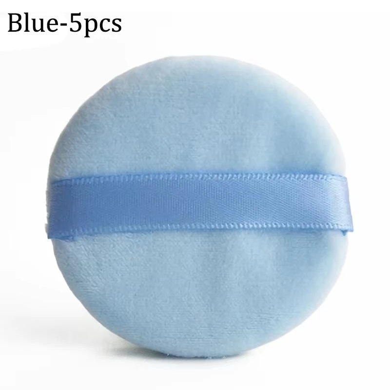 A round, light blue velvet makeup puff with a blue strap.