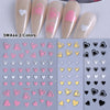 Un set de six autocollants pour ongles en forme de cœur, dans des tons de rose, blanc et noir, pour manucures DIY.