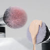 A close-up of a pink and gray makeup brush set with soft bristles on a white surface.