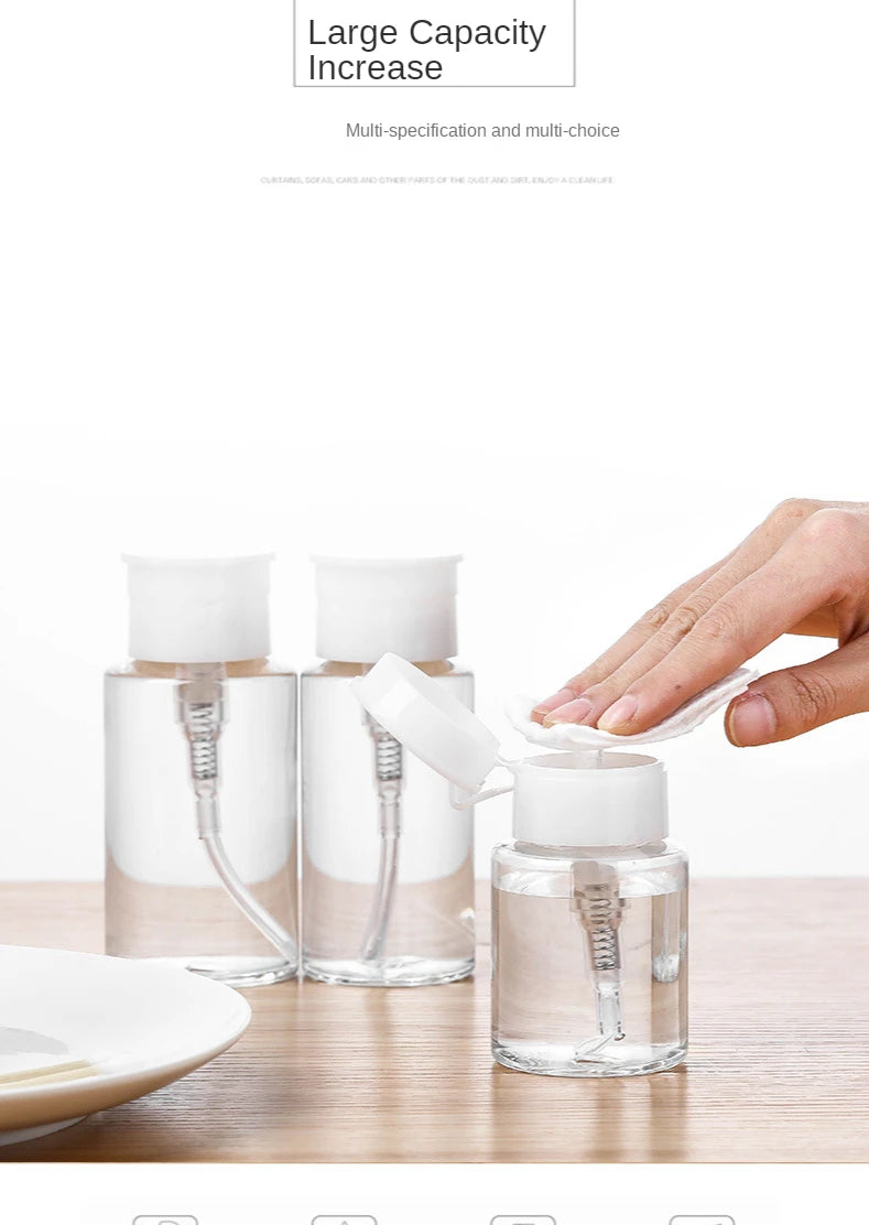 Three clear glass refillable pump dispenser bottles of liquid sitting on a wooden surface.