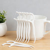 A white ceramic mug filled with reusable dental floss picks and a pair of dental floss picks on a wooden surface.