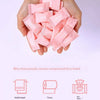 A hand holds a pile of pink compressed face towels and wet wipes for sensitive skin.