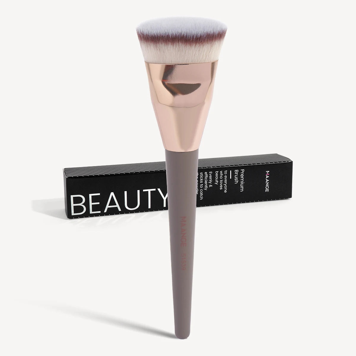 A professional flat kabuki foundation brush with a pink ferrule and dark handle resting on a black box.