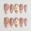 Set von zehn künstlichen Fingernägeln in Form von Mandelblüten mit durchscheinender rosa-weißer Marmorierung und vergoldetem 