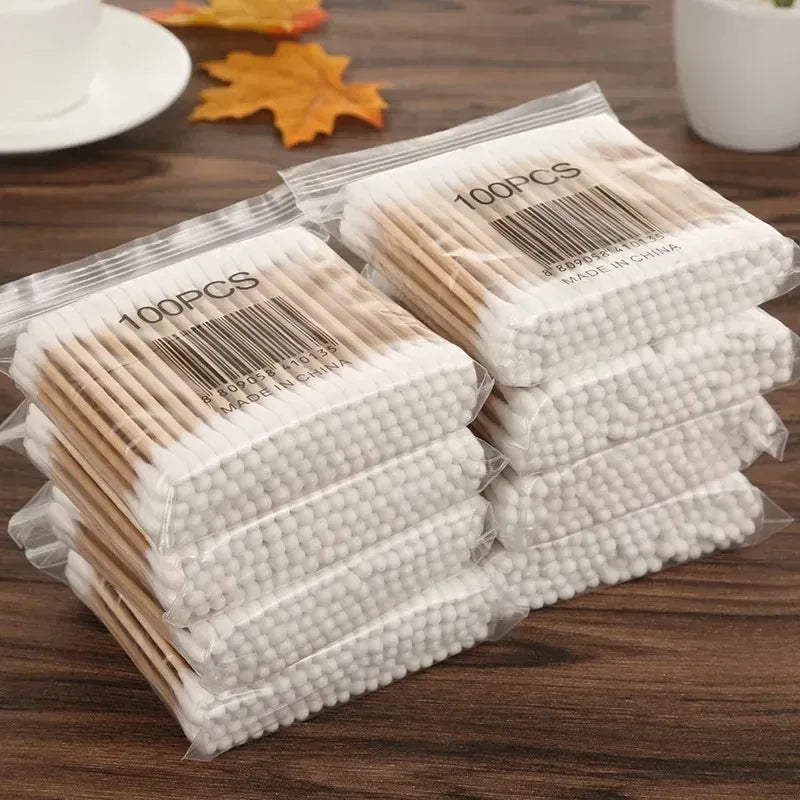 Eine Packung von 100 Paar doppelseitige Holz-Wattestäbchen zur Reinigung von Baby und Ohren auf einer Holzoberfläche.