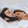 A man is sleeping peacefully with an anti-snoring chin strap placed on his face, next to a woman.
