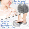 A close-up of a textured shower foot scrubber mat being used to rub the back and feet.