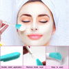 A woman applies a white facial mask using a silicone brush applicator on her face.