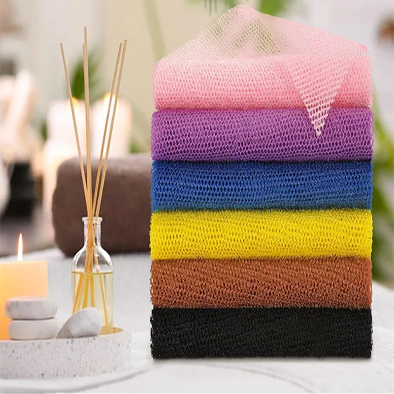 A stack of exfoliating mesh body scrubbing towels in various colors including pink, purple, blue, yellow, brown, and black.