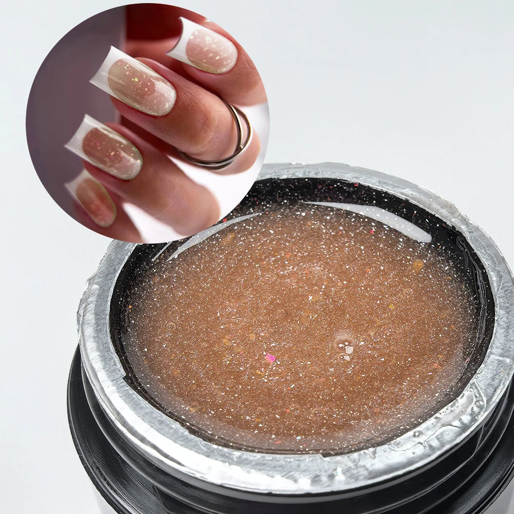 Une main montre une extension de ongles avec un vernis scintillant rose pâle, à côté d'un pot de constructeur gélifiant brun 