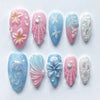 Kollektion von 10 Press-on-Falschnägeln mit floralen und irisierenden Designs in Pink, Blau und Weiß.