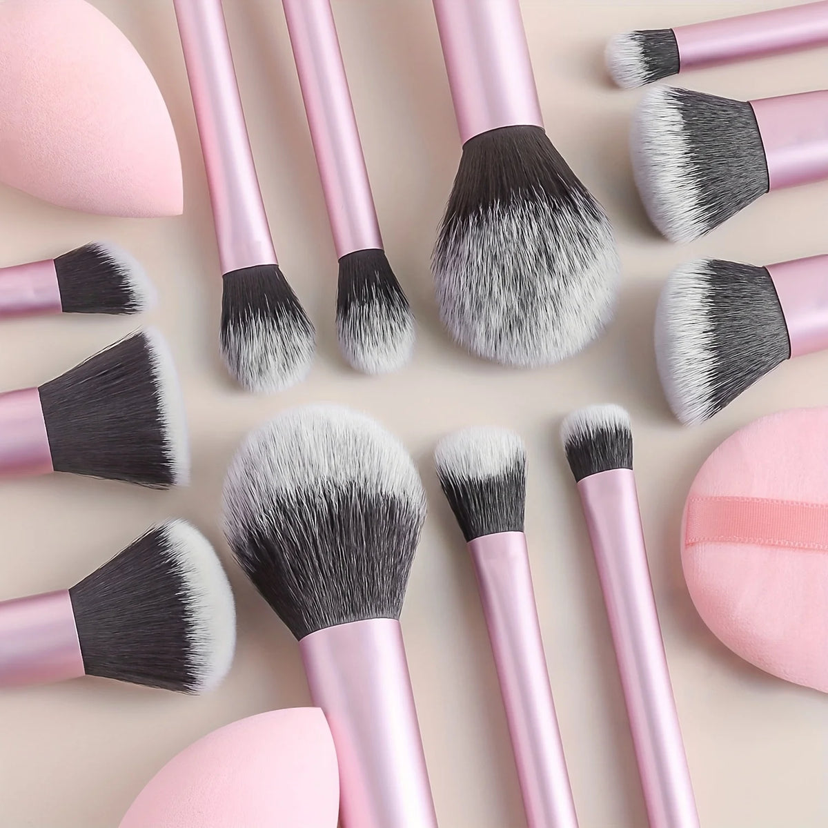 Una colección de 12 brochas de maquillaje profesionales en tonos rosa y negro, dispuestas sobre un fondo claro.