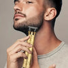 A man is holding a vintage gold-colored rechargeable hair clipper trimmer against his neck.