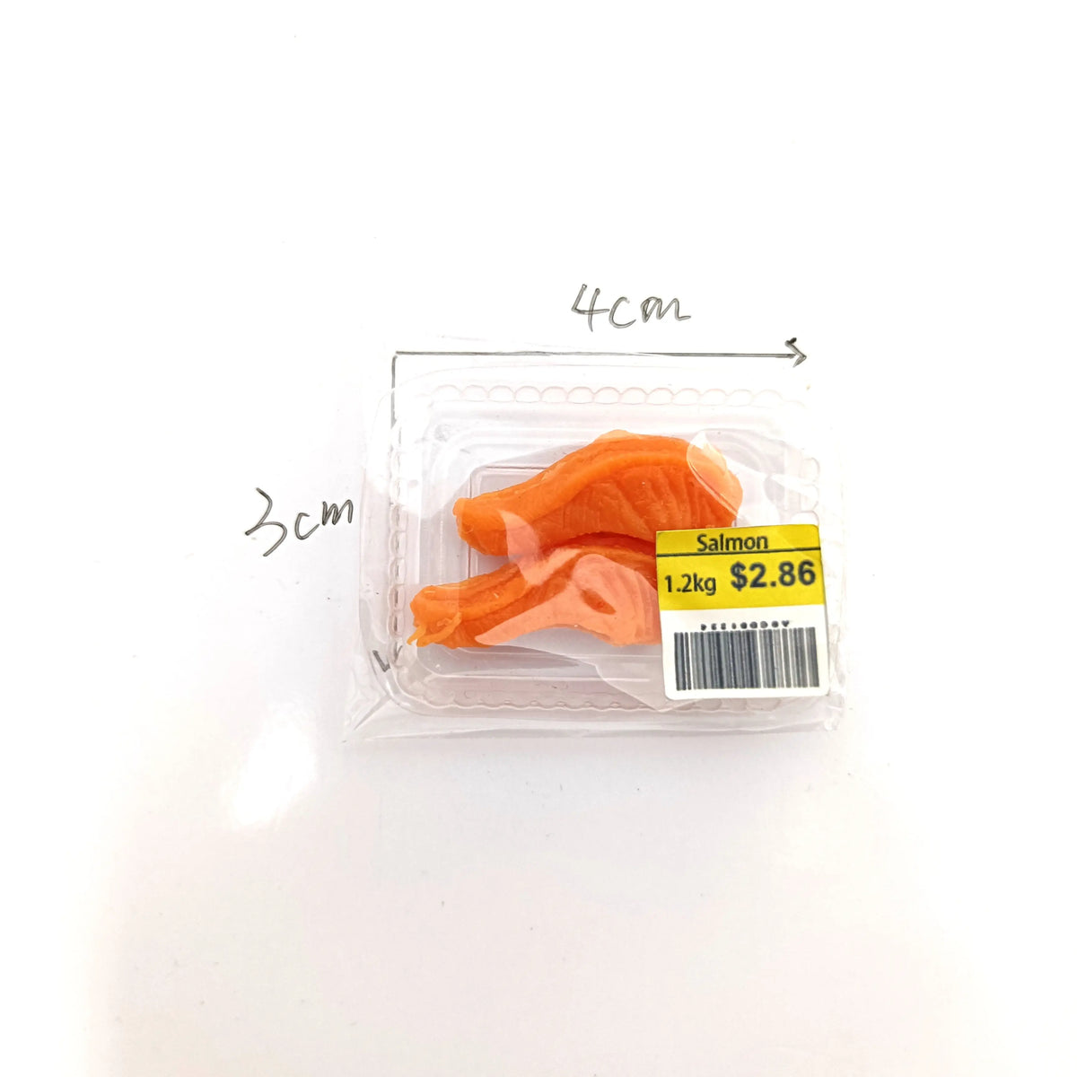 Un emballage plastique transparent contenant des morceaux de simulation de nourriture pour saumon avec des dimensions indiqué