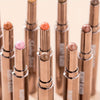 A row of metallic bronze eyeshadow sticks with double brushes displayed vertically.