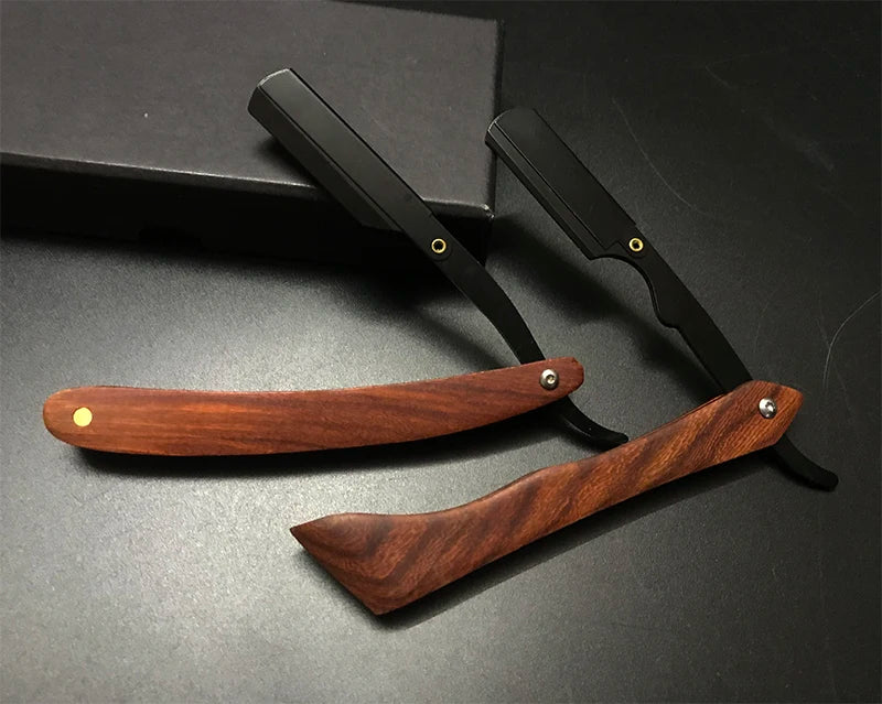 Un juego de maquinillas de afeitar manuales profesionales con mangos negros y cuchillas de madera sobre una superficie oscura