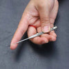 A hand holds a titanium keychain toothpick set with a silver handle and a pointed tip.
