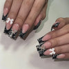 A close-up of a hand displaying Y2K sweet stars press-on nails with a black and white French wave design.