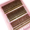 Une boîte d'extensions de faux cils naturels et fins de différentes nuances présentées dans un plateau rose.