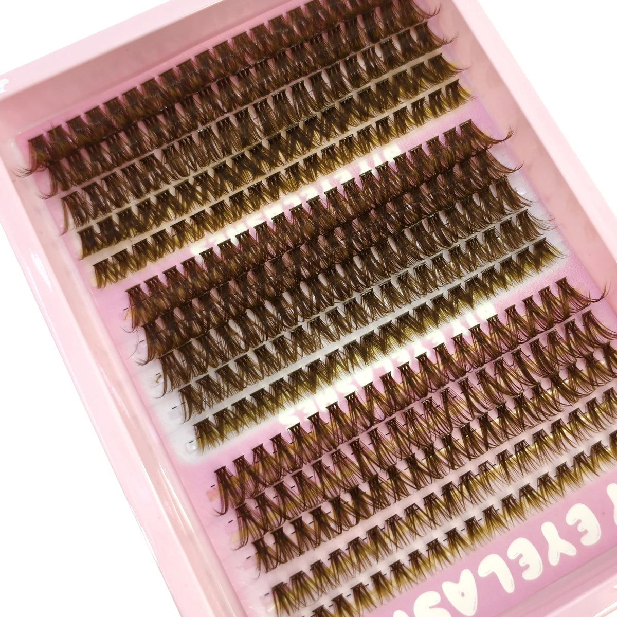 Une boîte d'extensions de faux cils naturels et fins de différentes nuances présentées dans un plateau rose.