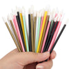 A hand holds a set of precision makeup brushes featuring various colors including black, pink, yellow, and white.