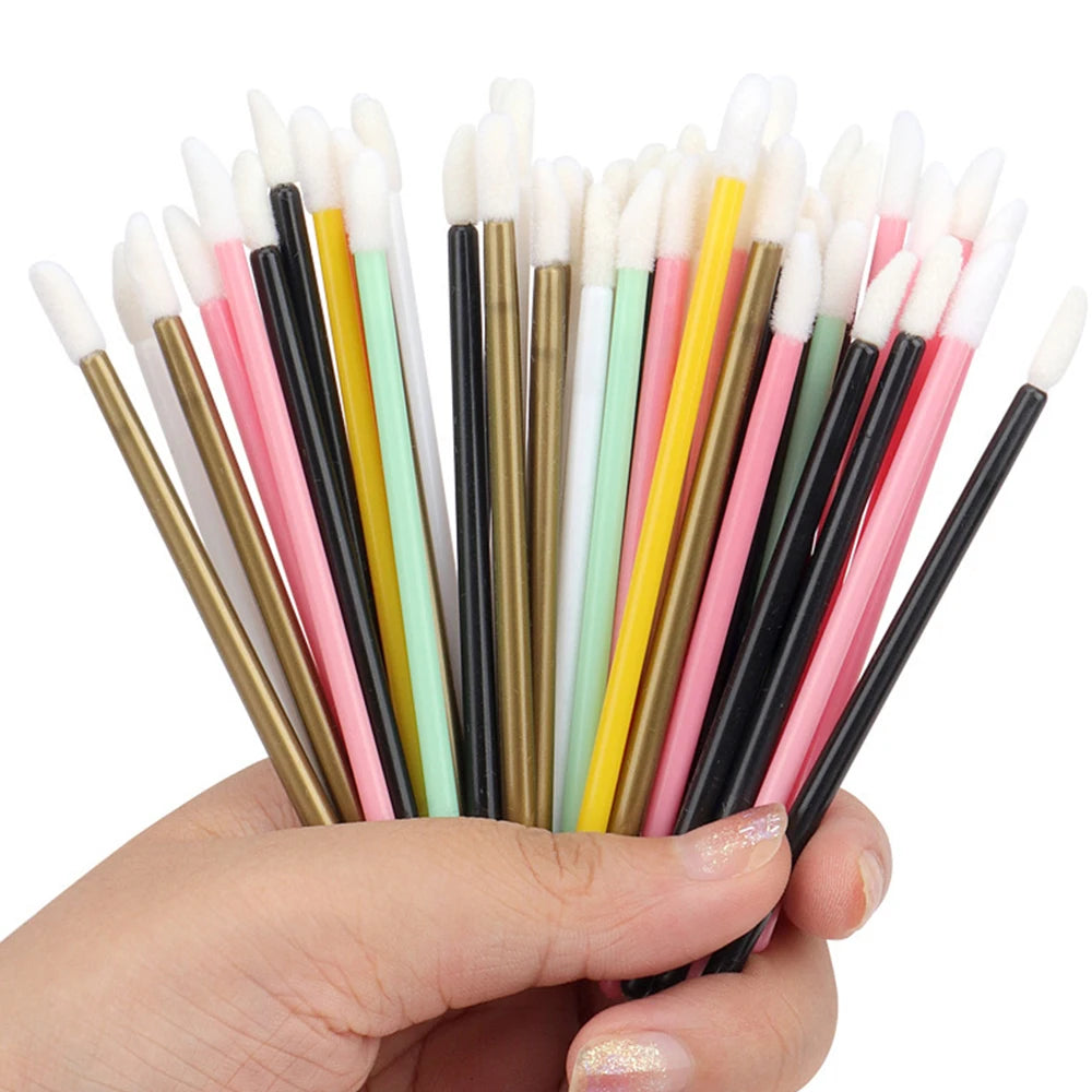 A hand holds a set of precision makeup brushes featuring various colors including black, pink, yellow, and white.