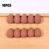 Ten pink makeup sponge puffs arranged in a row on a wooden surface.