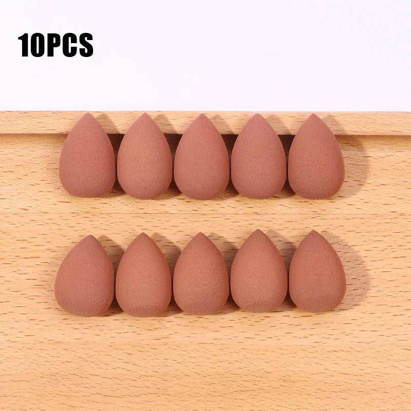 Ten pink makeup sponge puffs arranged in a row on a wooden surface.