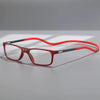 A pair of red-framed reading glasses with gray temples resting on a light gray surface.