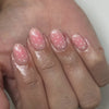 Close-up of a hand displaying red and pink striped press-on almond shaped nails with white dots