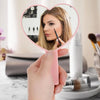 Une main tient un miroir en forme de cœur rose reflétant le visage et les cils d'une femme.