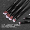 A set of black makeup brushes with pink and purple synthetic bristles displayed on a dark surface.