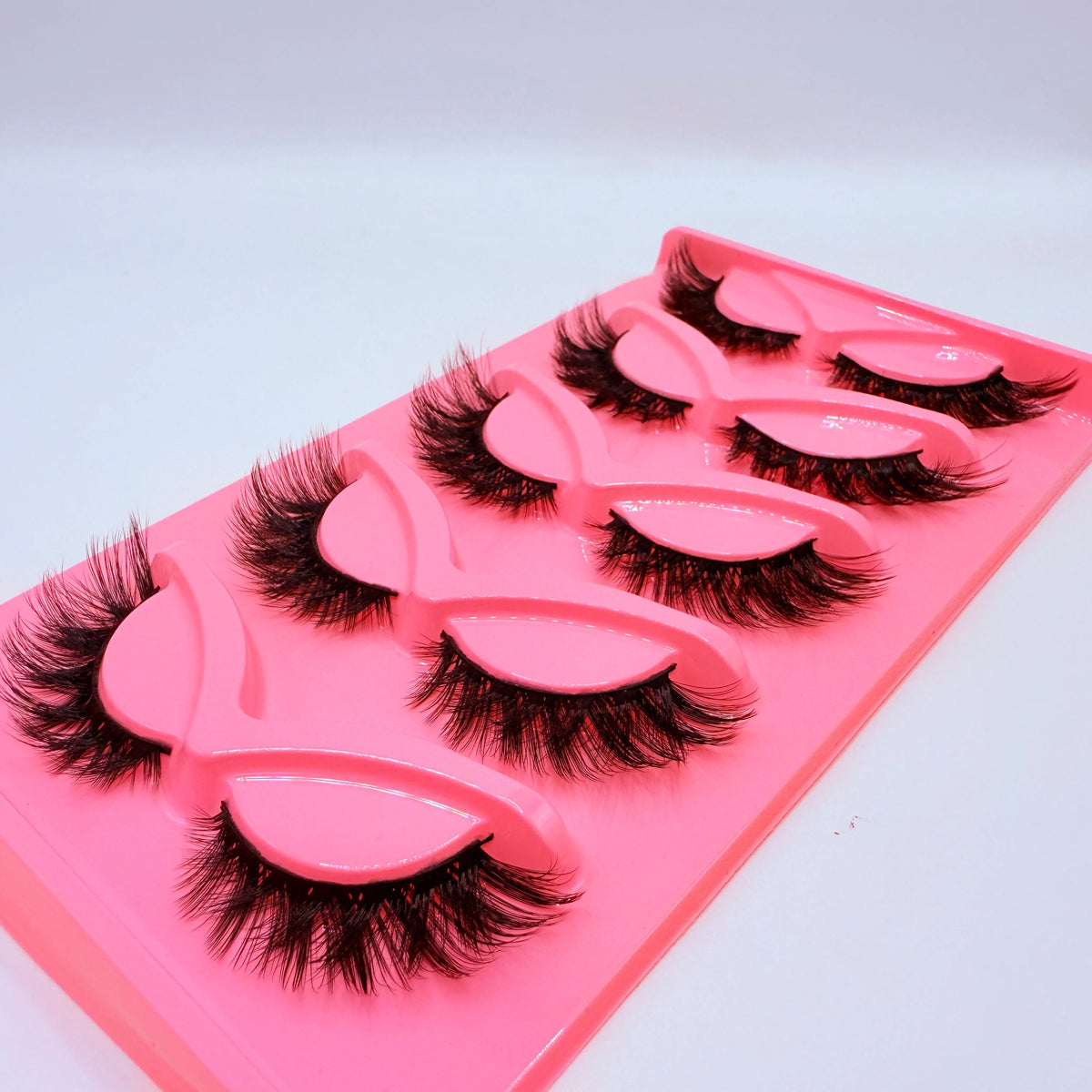 Un plateau en plastique rose contenant cinq paires de faux cils dramatiques.