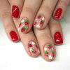 A set of press-on acrylic nails featuring a red and white strawberry floral design on a natural pink base.