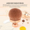 Une grande brosse de maquillage ronde, couleur cuivre, est montrée à côté de produits cosmétiques.