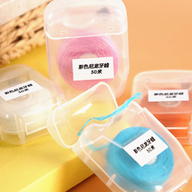 Various colors of 50m disposable nylon dental floss spools in clear plastic containers.