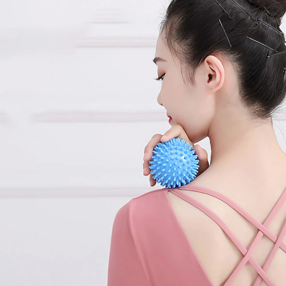 A woman is using a blue deep tissue massage ball on her neck and shoulder area.