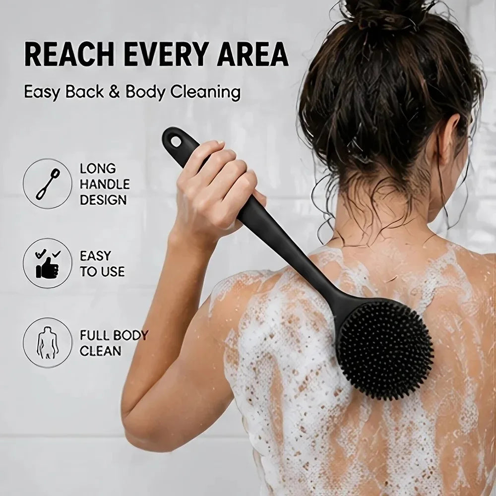 A woman is using a black long handle silicone body brush to clean her back with soap foam.